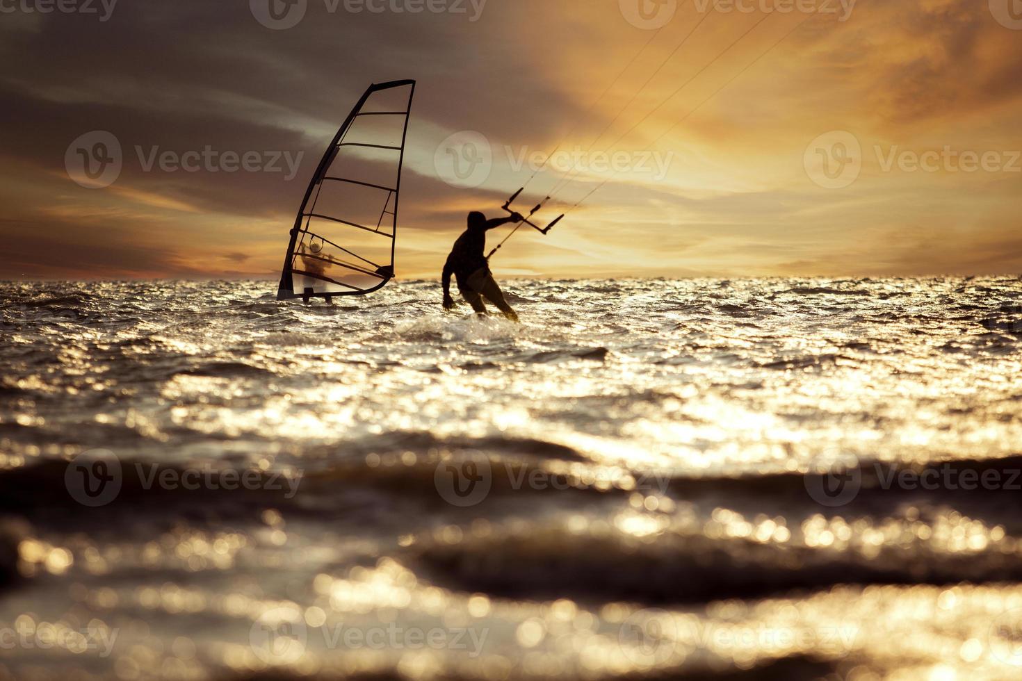 silhouette photography of man playing kite surf and wind surf over rushing sea level against beautiful sunset sky photo