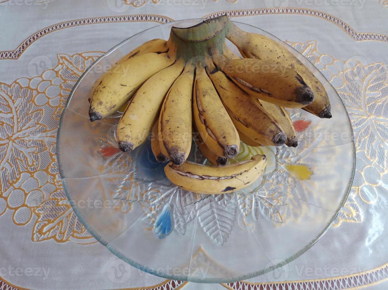 Fresco amarillo bananas en un plato en mesa foto