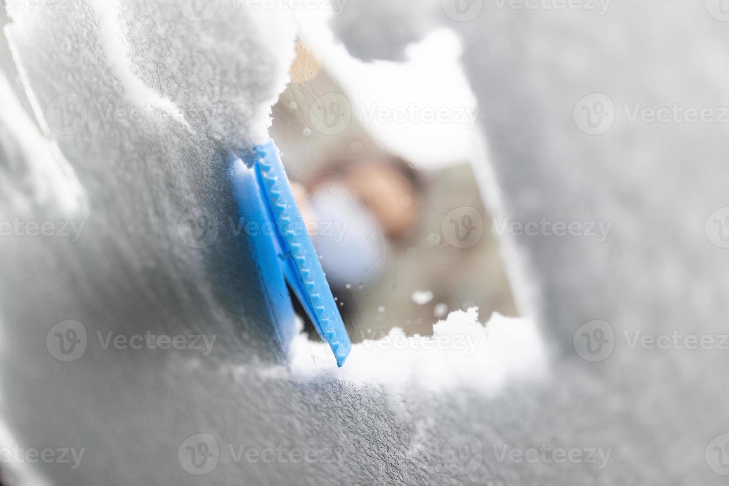 Women hand removes snow from car windshield in winter day, cleaning car from snow photo
