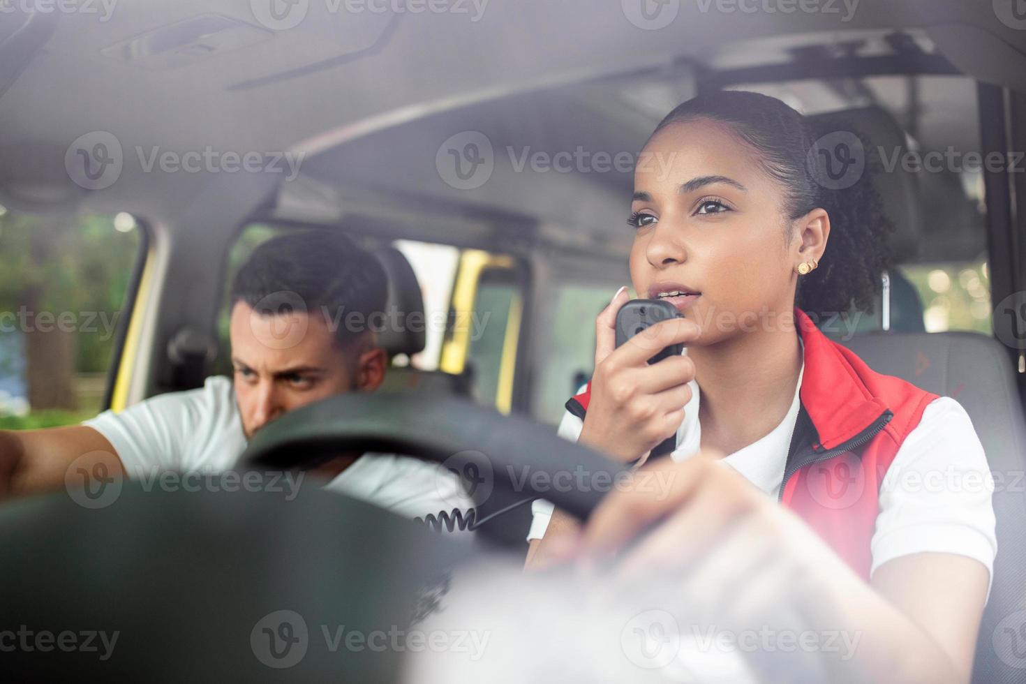 attractive young paramedic sitting in ambulance and looking away. Young woman answering a call in an ambulance. She's with her colleague. photo