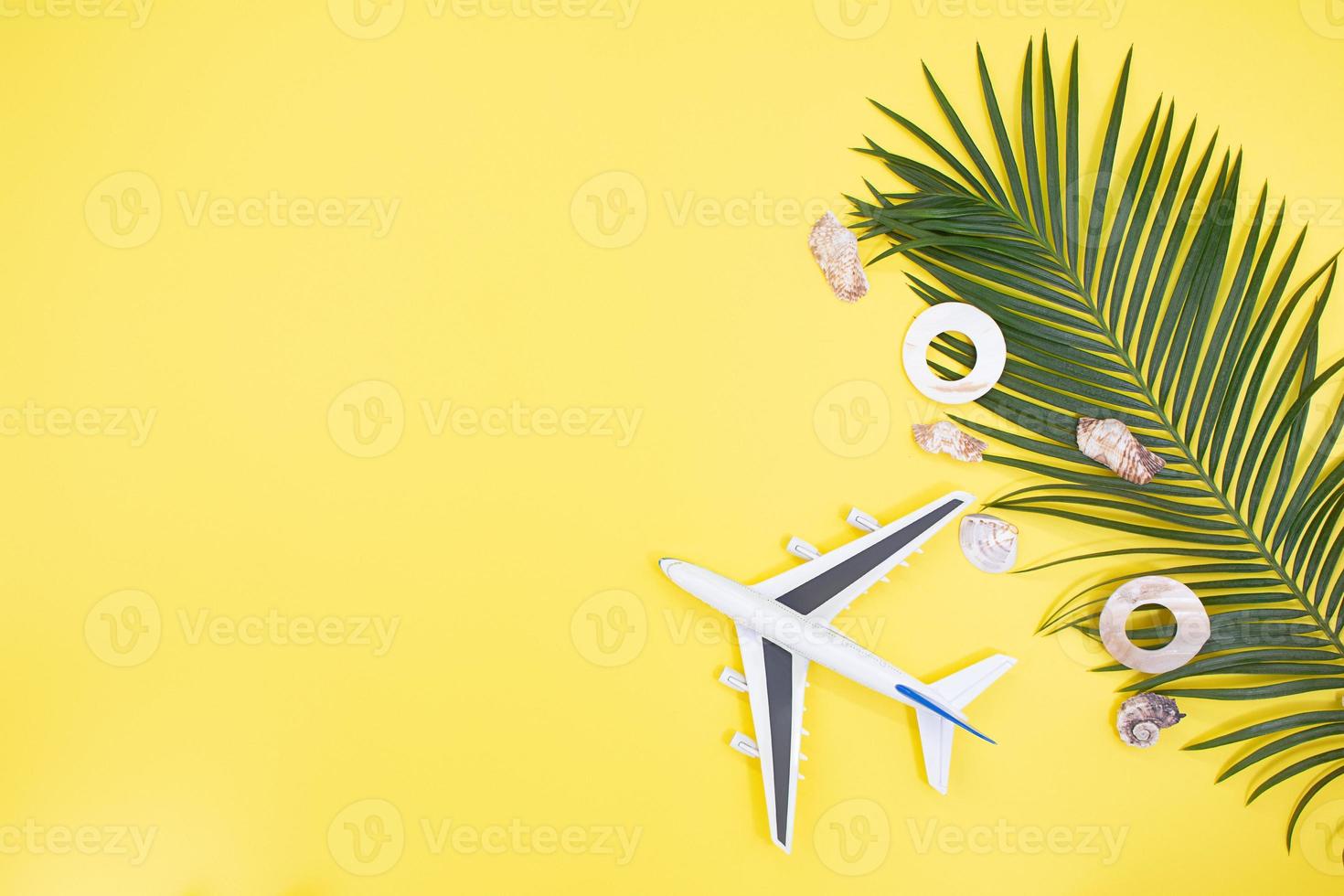 White plane, shells with palm on yellow background. Concept of summertime, vacation, travel. Copy space photo
