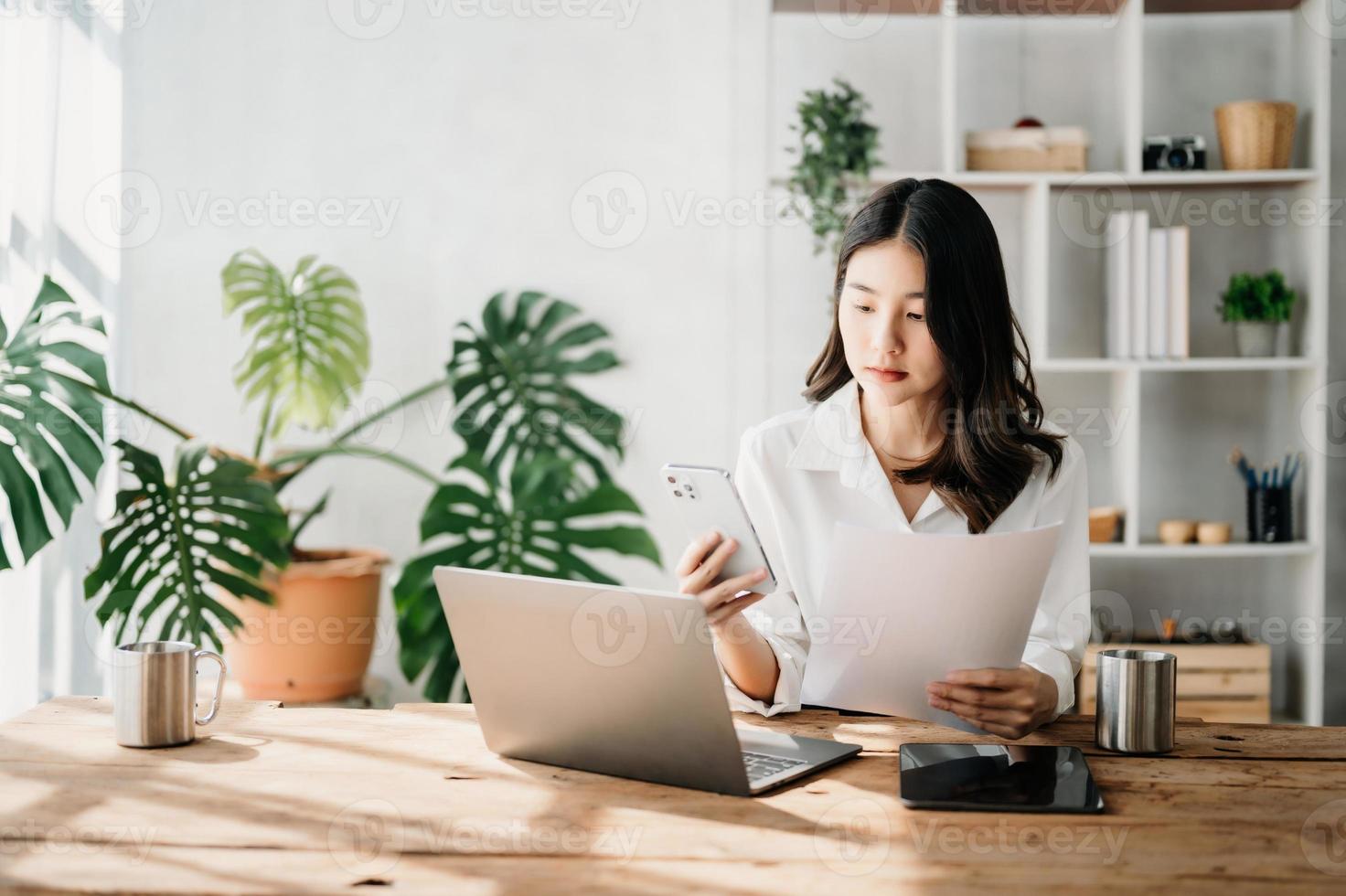 hermosa asiático negocio mujer mecanografía ordenador portátil y tableta metido a el mesa a hogar oficina foto