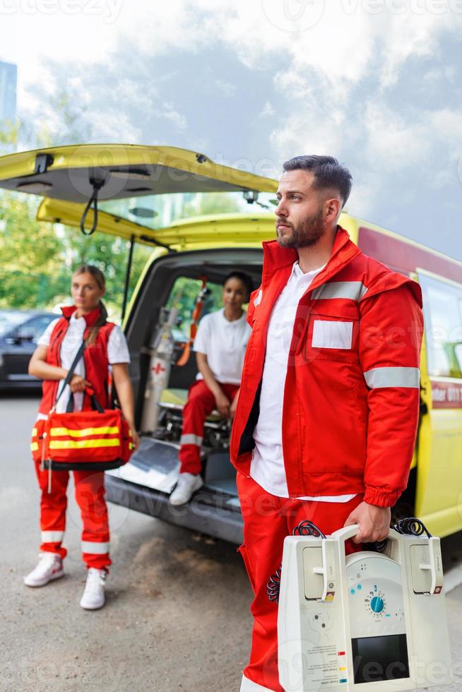 Paramedic nurse and emergency doctor at ambulance with kit. a paramedic, standing at the rear of an ambulance, by the open doors. photo