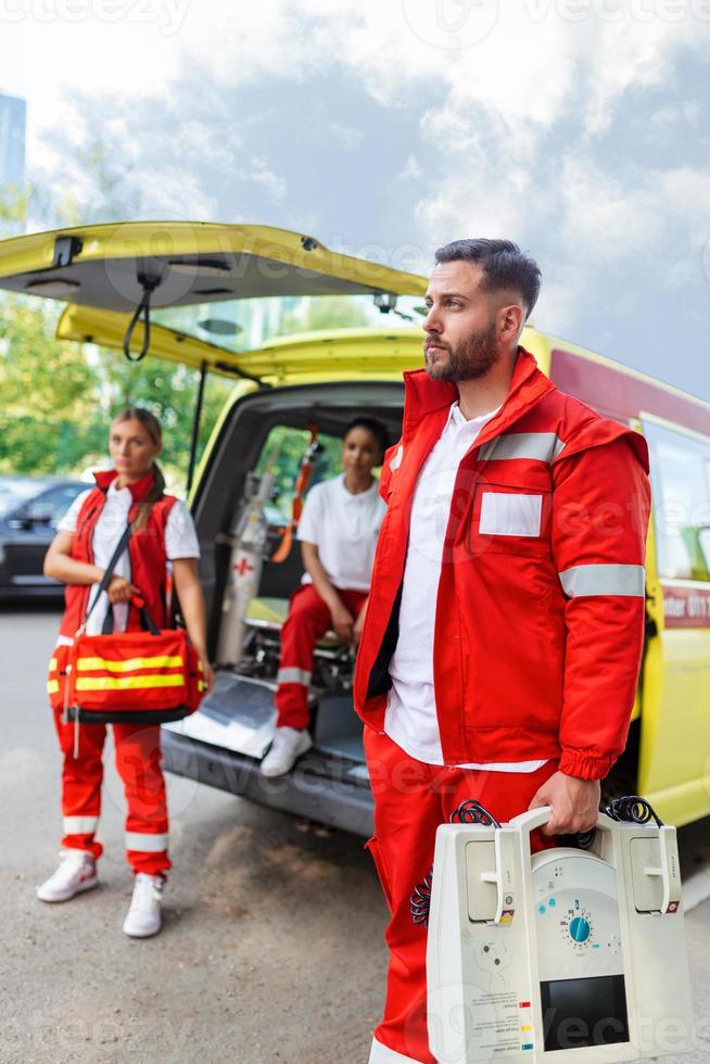 paramédico enfermero y emergencia médico a ambulancia con equipo. un paramédico, en pie a el posterior de un ambulancia, por el abierto puertas foto