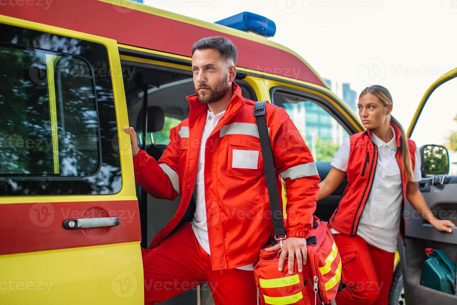 Paramedic nurse and emergency doctor at ambulance with kit. a paramedic, standing at the rear of an ambulance, by the open doors. photo