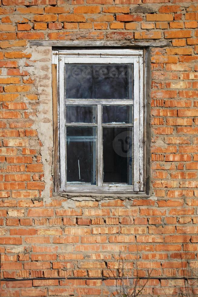 Vertically brick wall with a window in an old rustic frame. photo