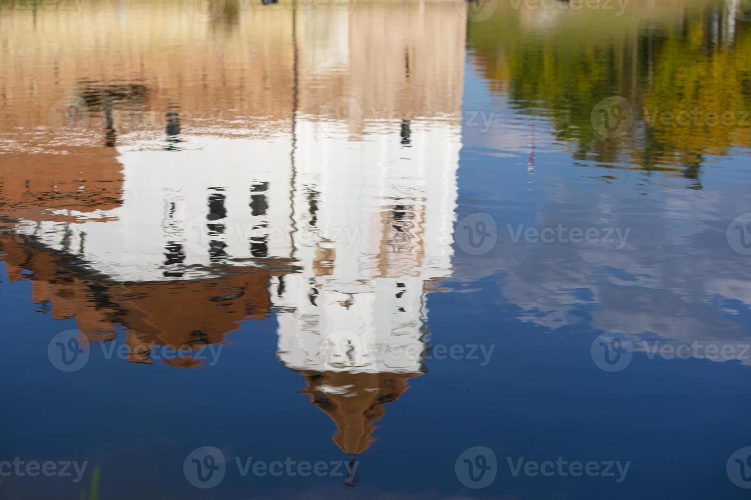 Reflection of an old castle in blue water. photo