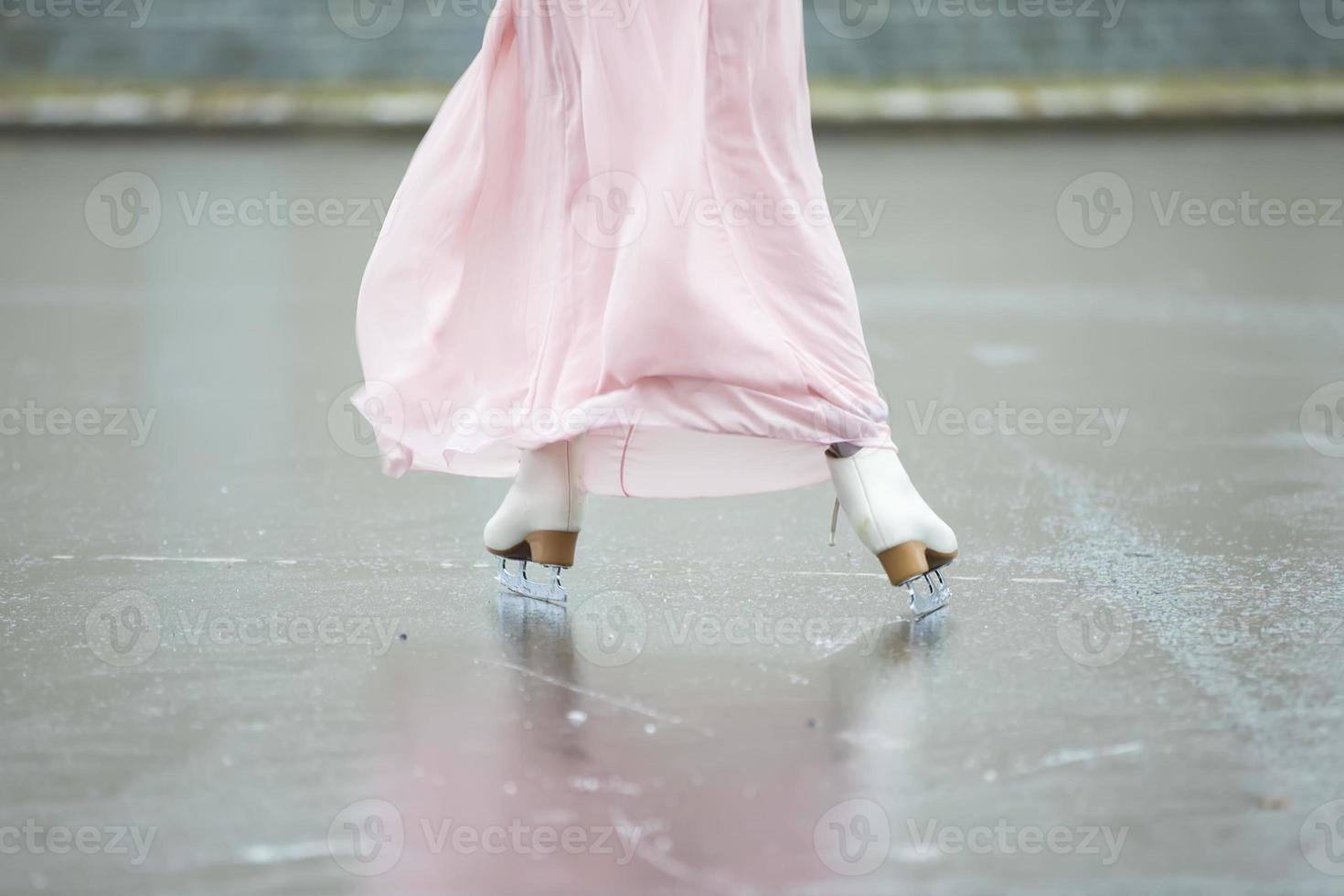 Close-up of female legs on white figure skates in winter at an outdoor ice rink. photo
