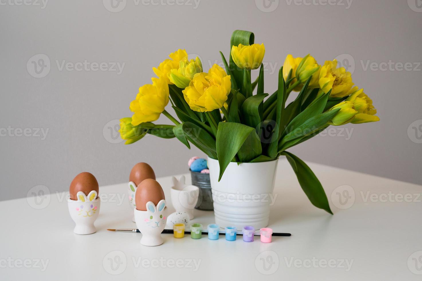 Easter banner with cute bunny shaped egg holders in pastel colors near tulips. Paint eggs. photo