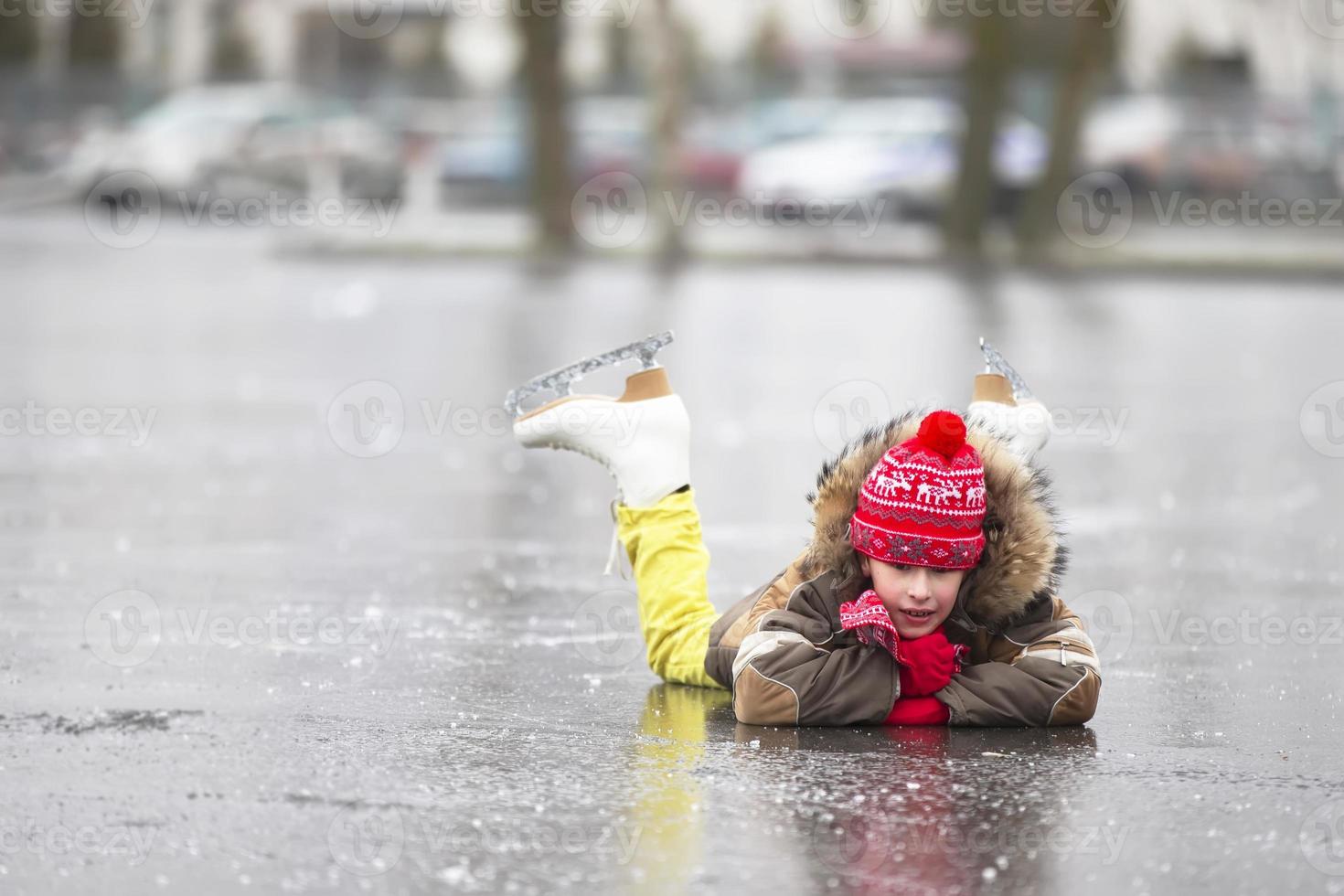 un chico en calentar ropa y figura patines mentiras en el hielo. foto