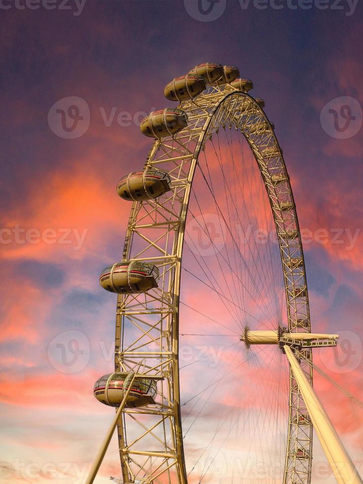 ferris rueda en el diversión parque en antecedentes de puesta de sol cielo con nubes bajo ángulo ver de un grande ferris rueda. foto