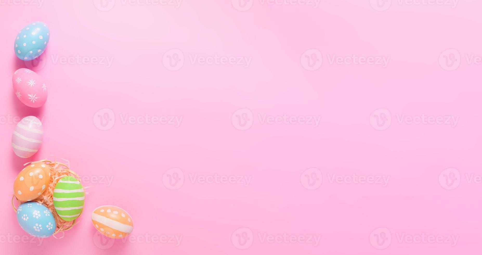 Happy Easter holiday greeting card concept. Colorful Easter Eggs on pastel pink background. Flat lay, top view, copy space. photo