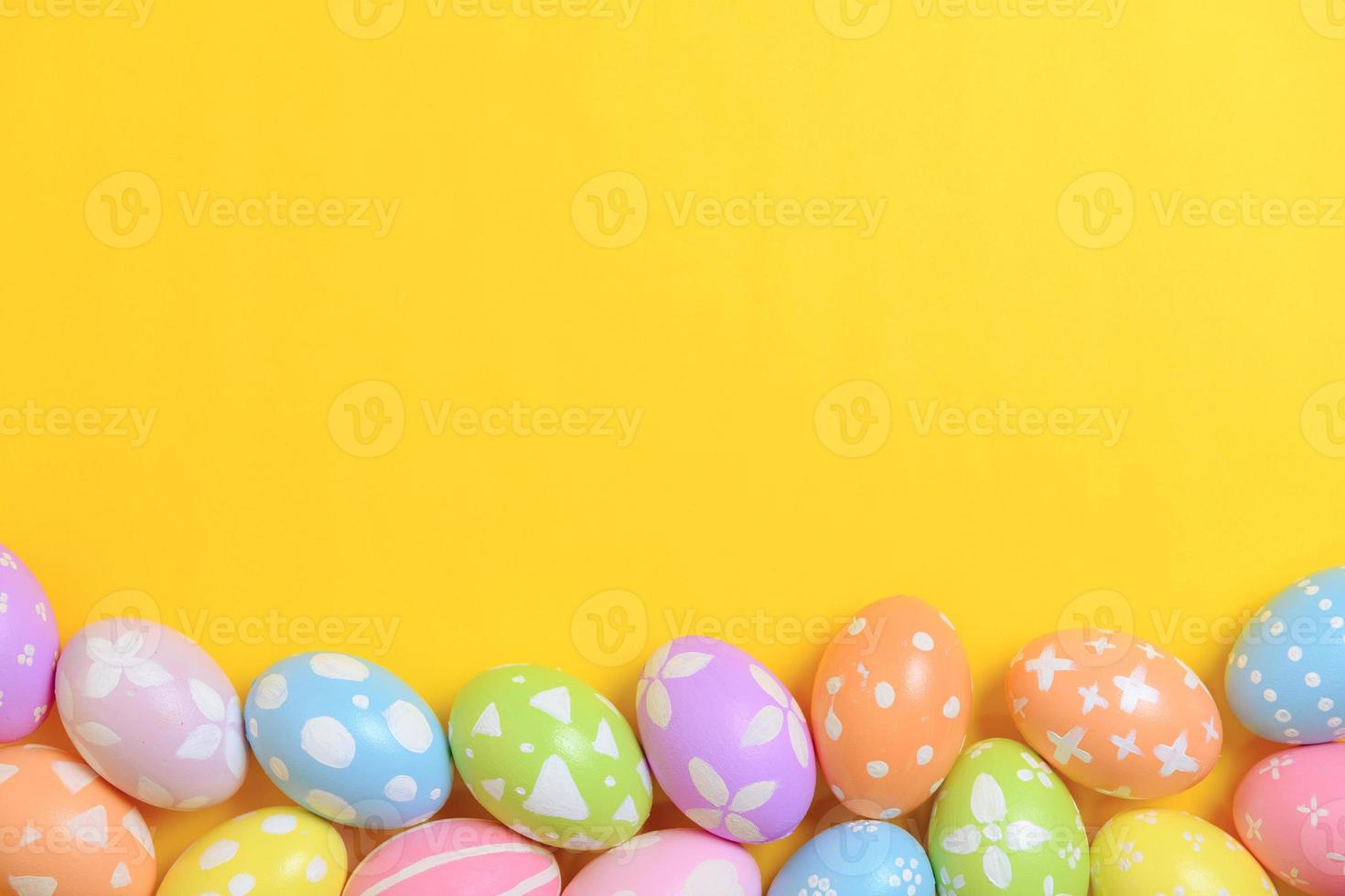 Happy easter holiday celebration concept. Group of painted colourful eggs decoration on a yellow background. Seasonal religion tradition design. Top view, flat lay, copy space. photo