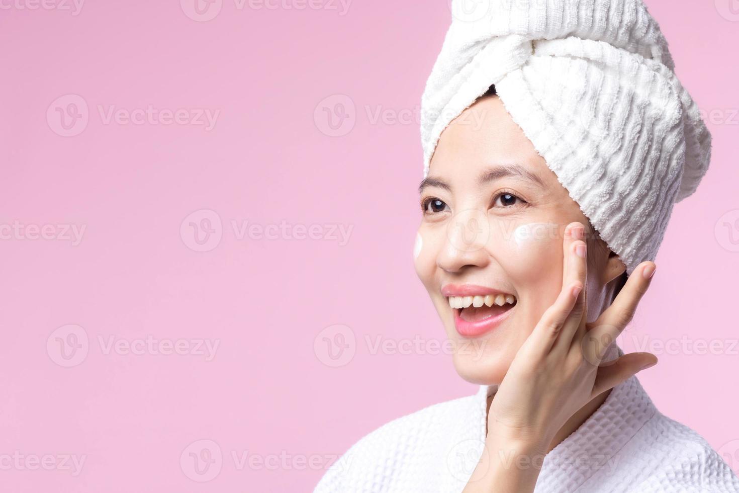 joven asiático mujer aplicando facial protección de la piel cara crema, cosmético hidratante en sano natural piel hacer arriba rostro. retrato brillante sonrisa niña persona modelo con cuidado belleza producto, spa, cosmetología. foto