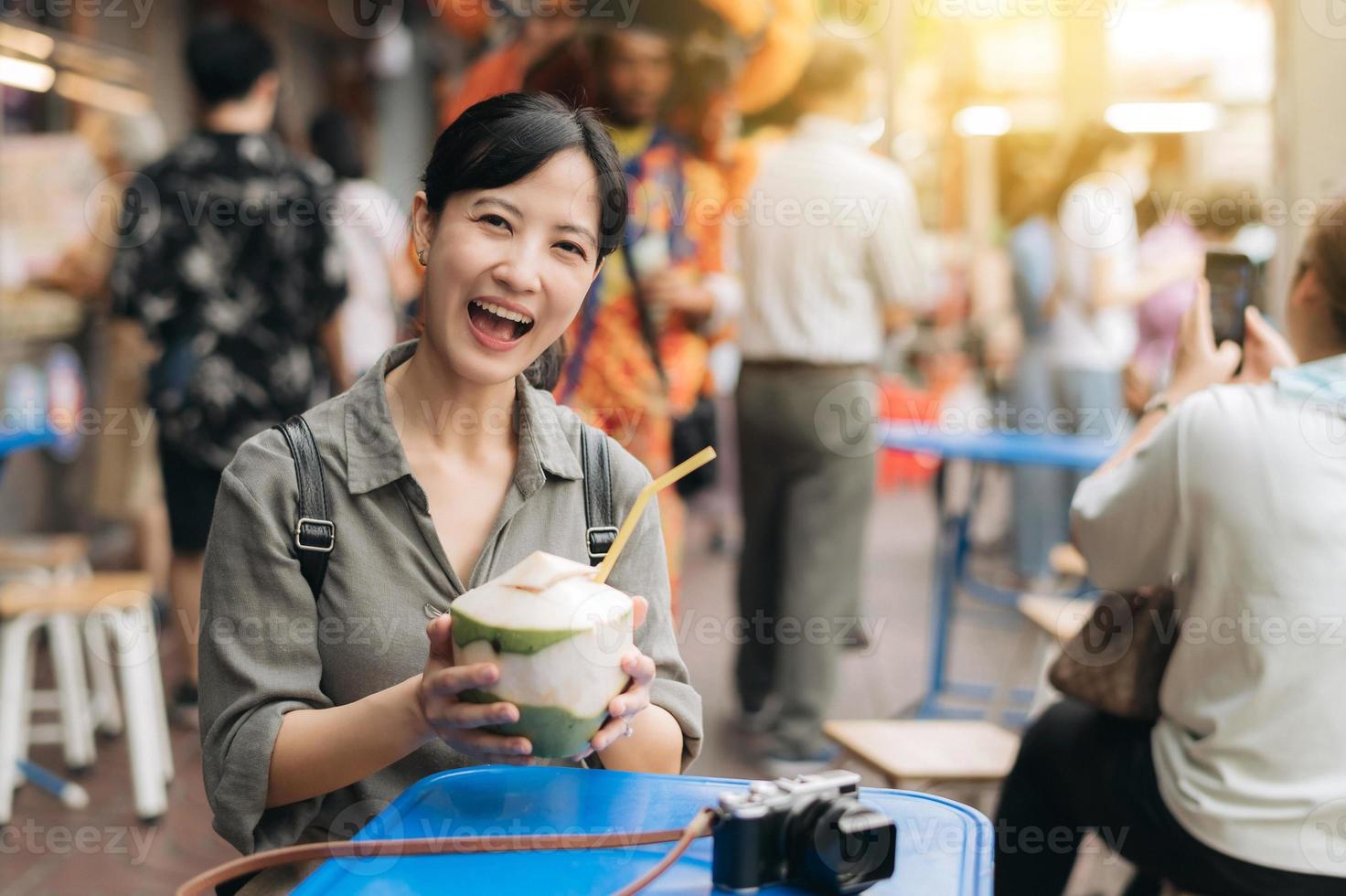 contento joven asiático mujer mochila viajero Bebiendo un Coco jugo a China pueblo calle comida mercado en bangkok, tailandia viajero comprobación fuera lado calles foto