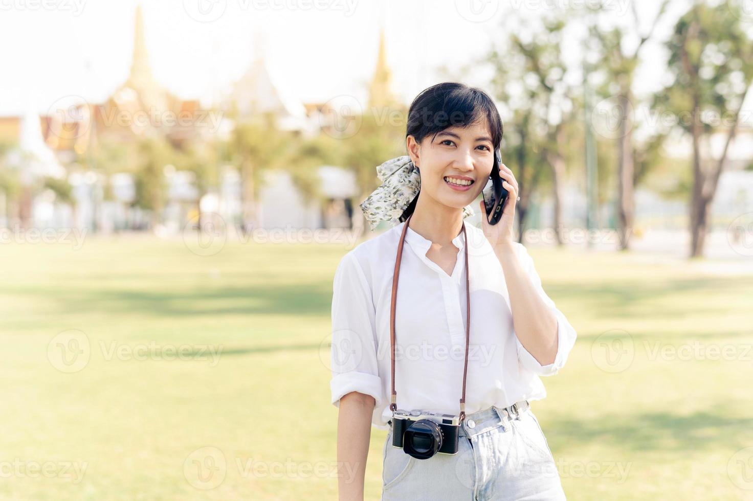 retrato hermosa joven asiático mujer con teléfono inteligente en verano fiesta vacaciones viaje con el grandioso palacio en un antecedentes a bangkok, Tailandia foto