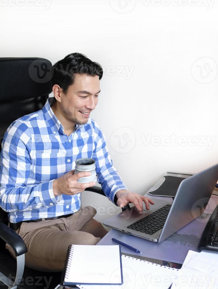 A man in a checked shirt working from home at a desk photo