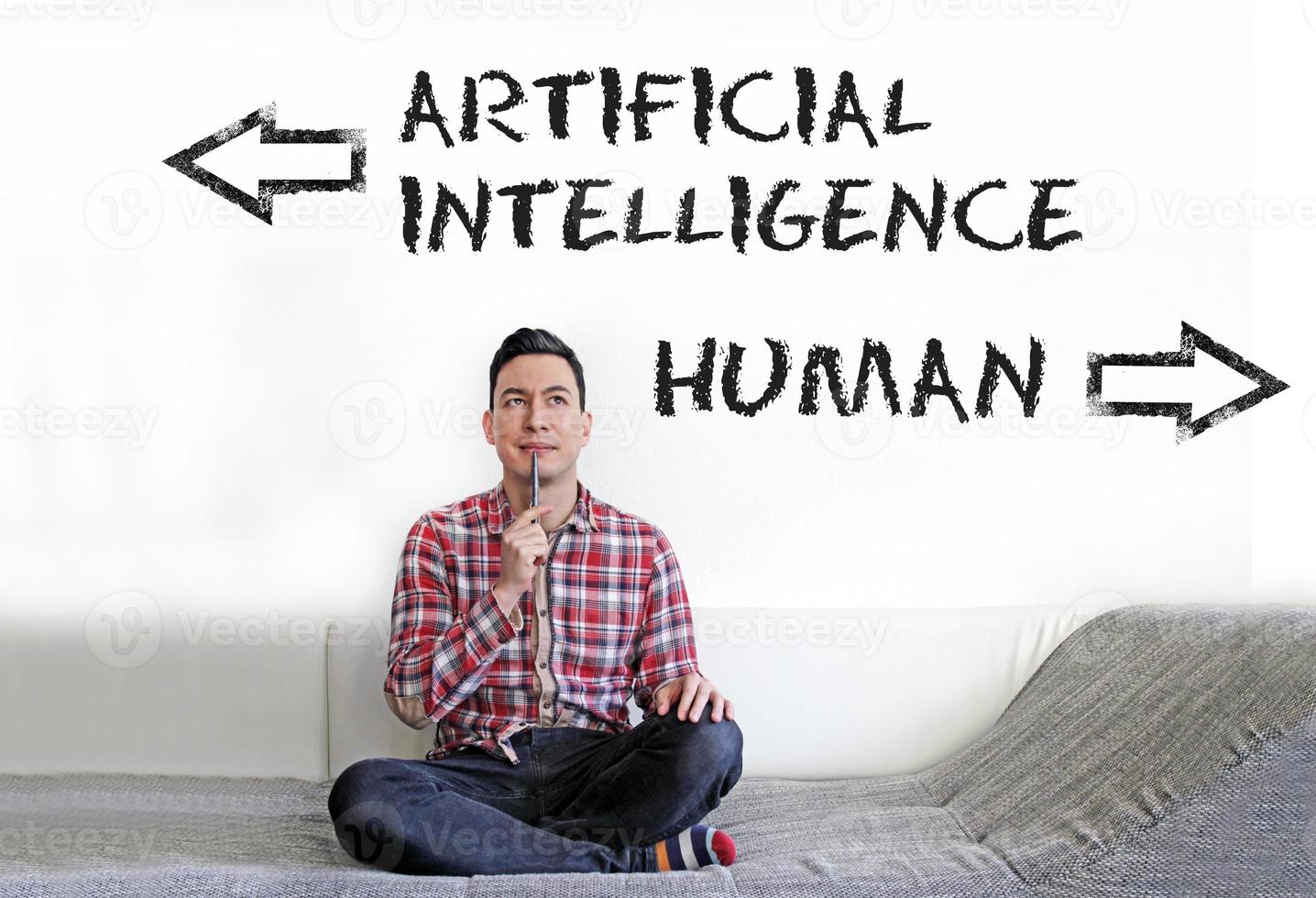 Man sitting on the couch with the words Artificial Intelligence and Human written on the wall next to him photo