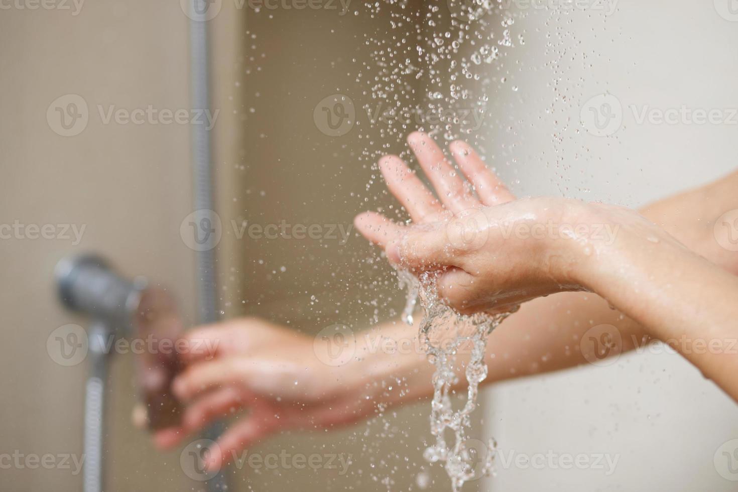 un mujer usos mano a medida el agua temperatura desde un agua calentador antes de tomando un ducha foto