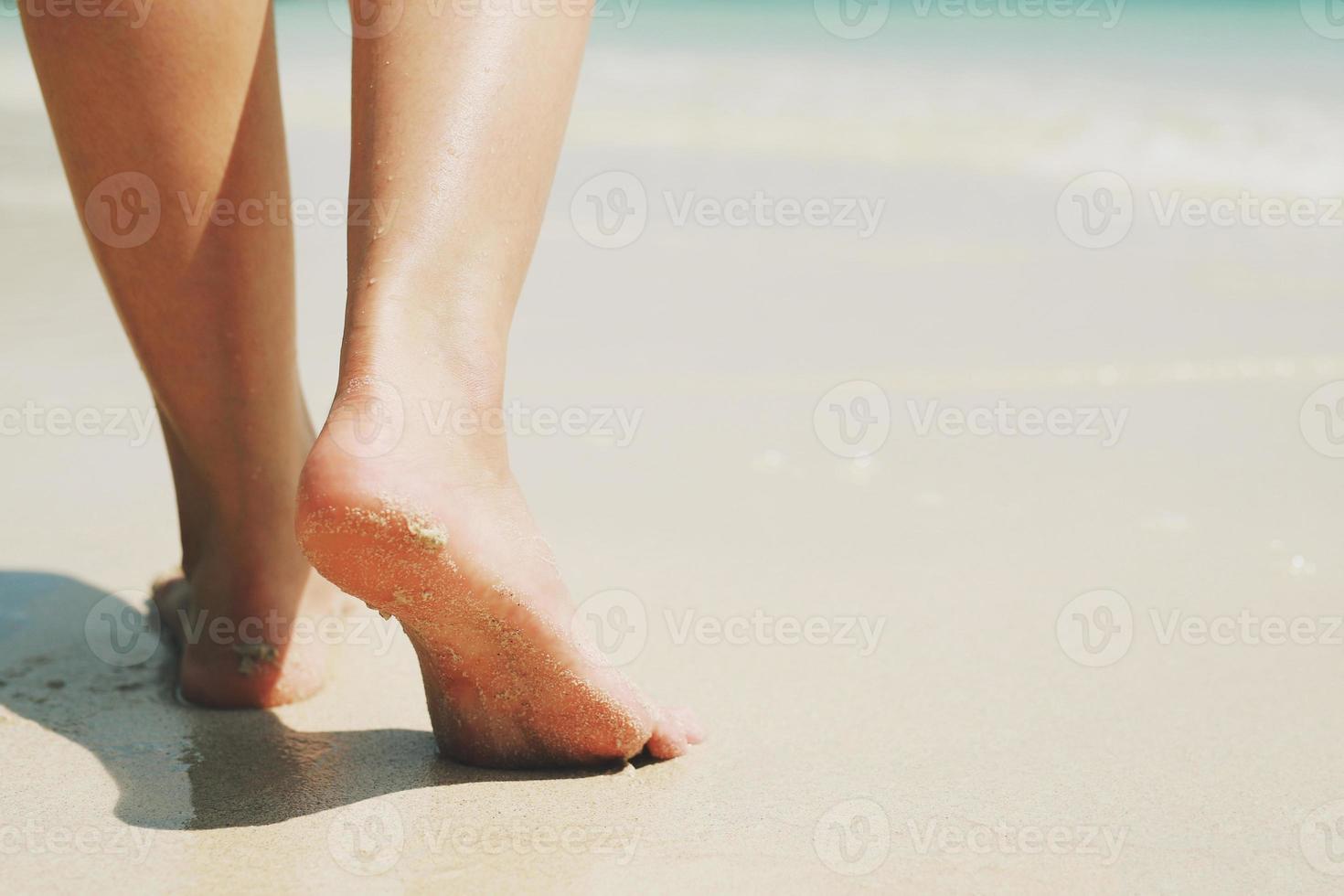 Close up of a lady woman's bare feet walking and footprint at wet on the beach. Vacation on ocean beach, foot on sea sand. Leave empty copy space Enter the text. Shadow from the sun hits the sand. photo
