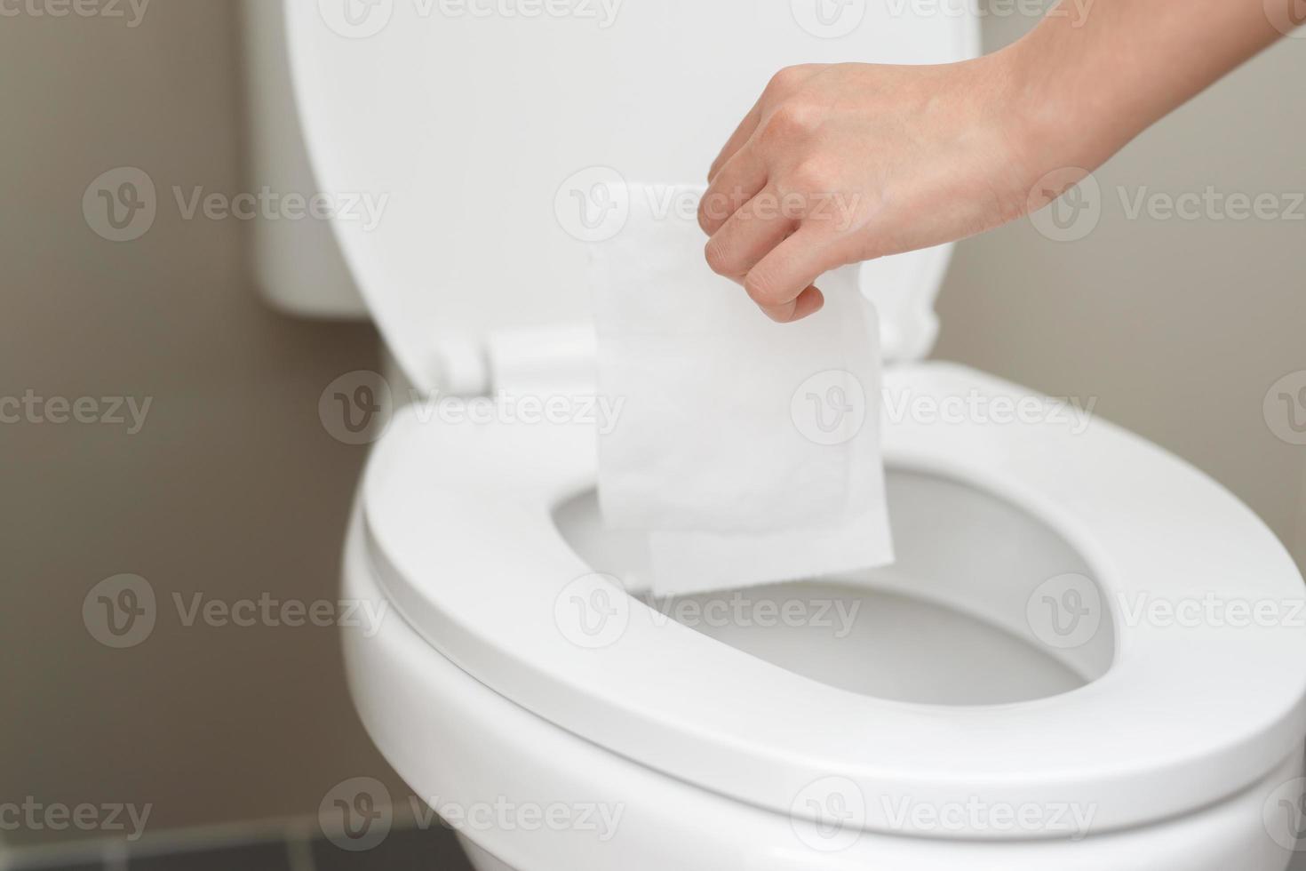 close up hand holding a tissue to be thrown into the toilet bowl. Can not drain water of toilet paper in the toilet bowl cause the stool to clog up. photo