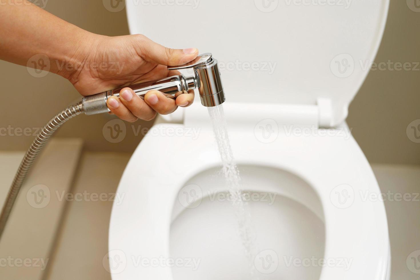 Cleaning staff examining the toilet sprayer. photo