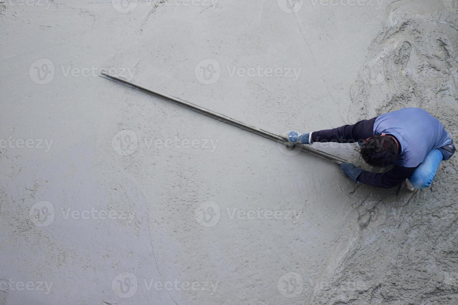 Workers plastering ready mixed concrete floor at the construction agency photo