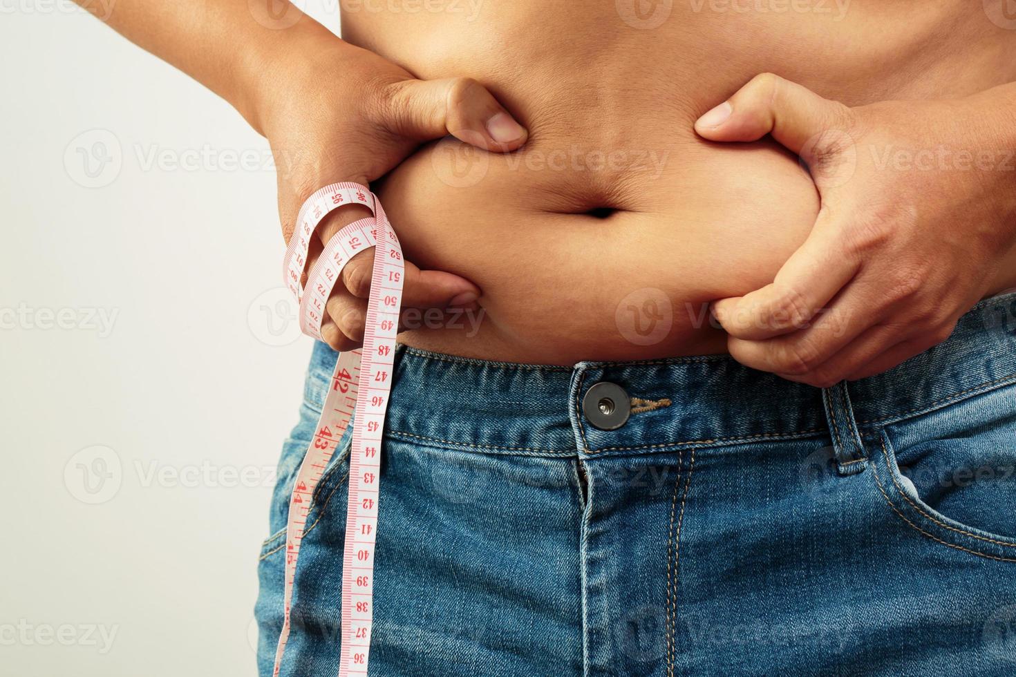 fat man check out body overweight abdomen his belly with in hand measuring tape photo