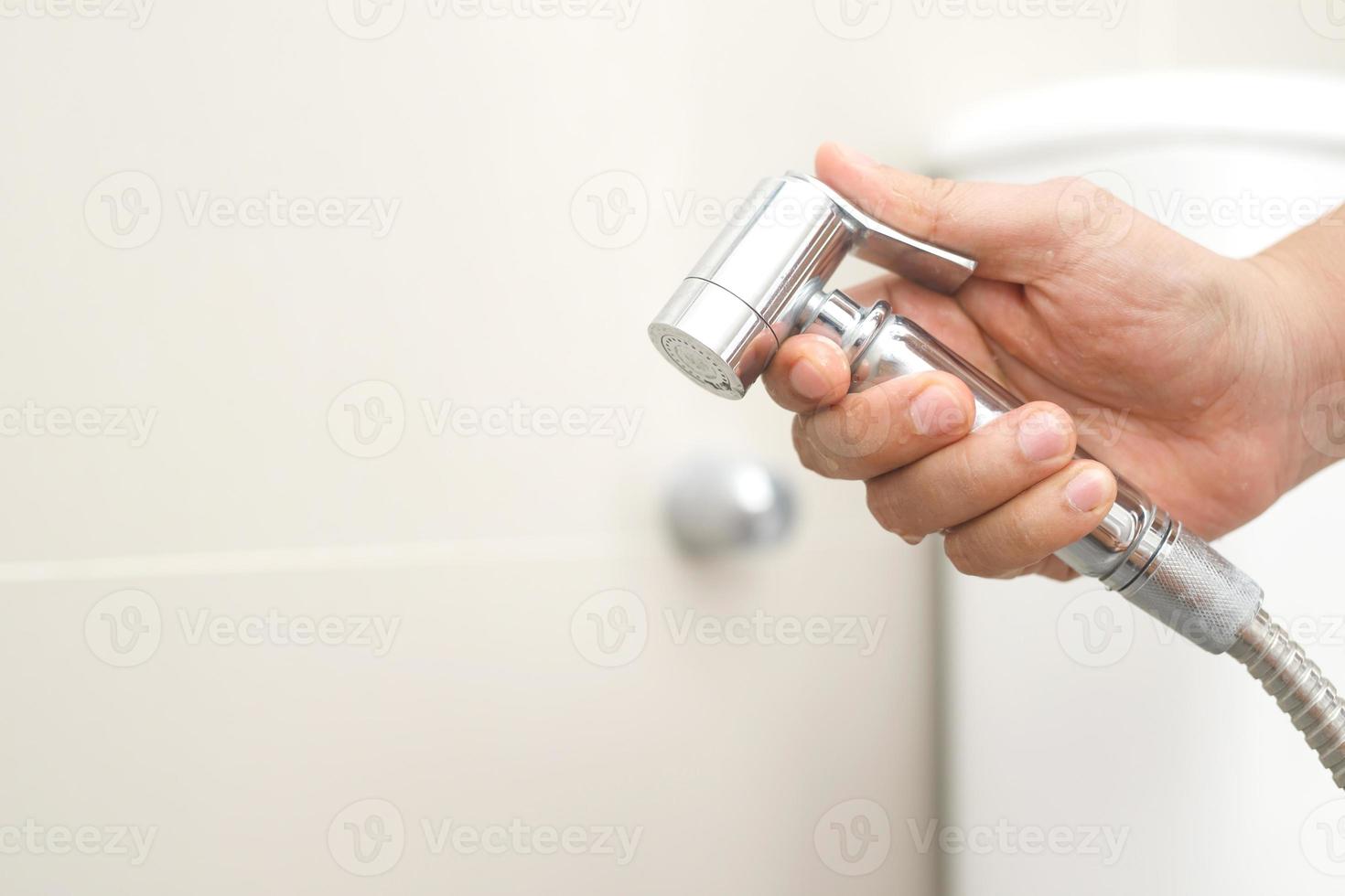 Cleaning staff examining the toilet sprayer. photo