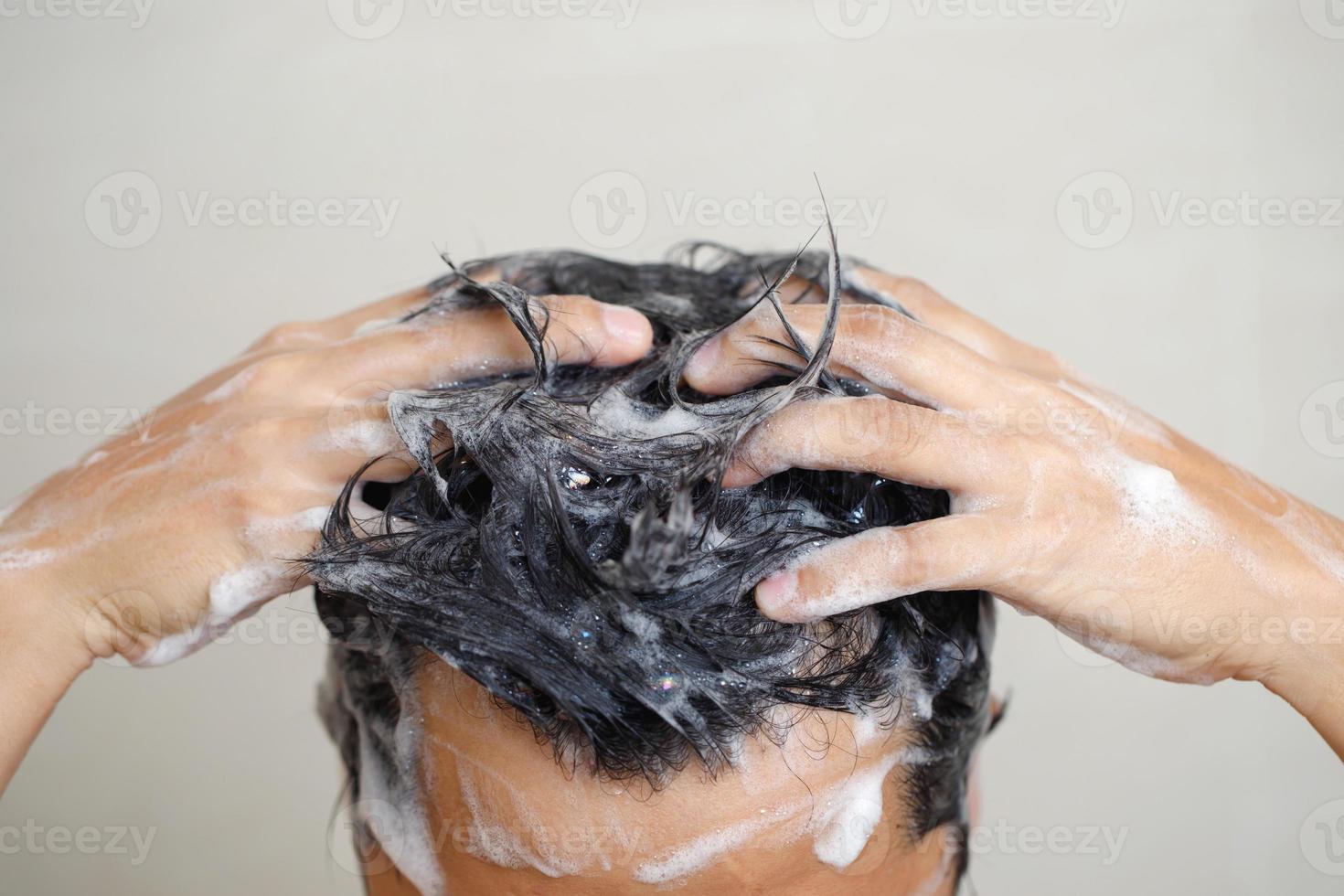 A man is washing his hair with shampoo photo