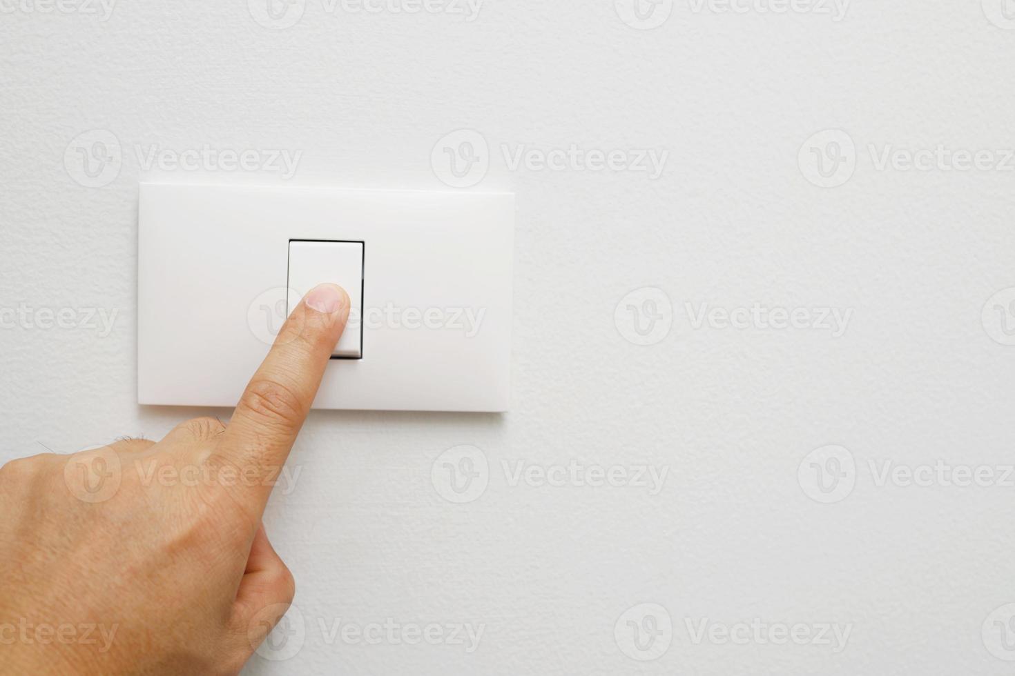 Turn off the light, close up female hand is closing the power switch. Save energy, reduce global warming. photo