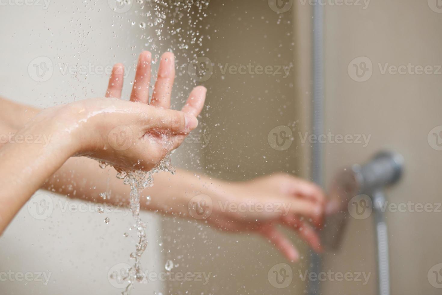 un mujer usos mano a medida el agua temperatura desde un agua calentador antes de tomando un ducha foto