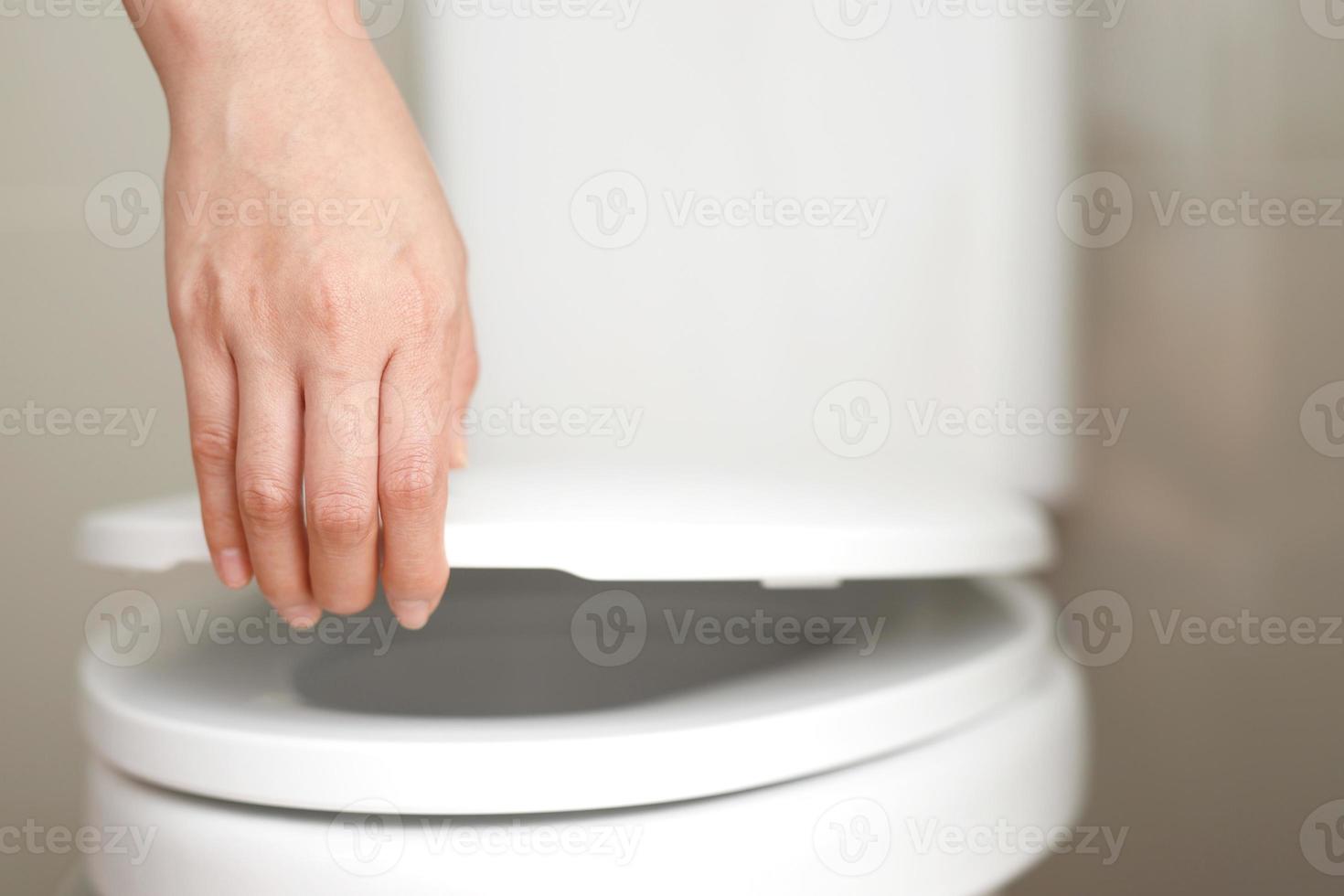 cerca arriba mano de un mujer clausura el tapa de un baño asiento. higiene y salud cuidado concepto. foto