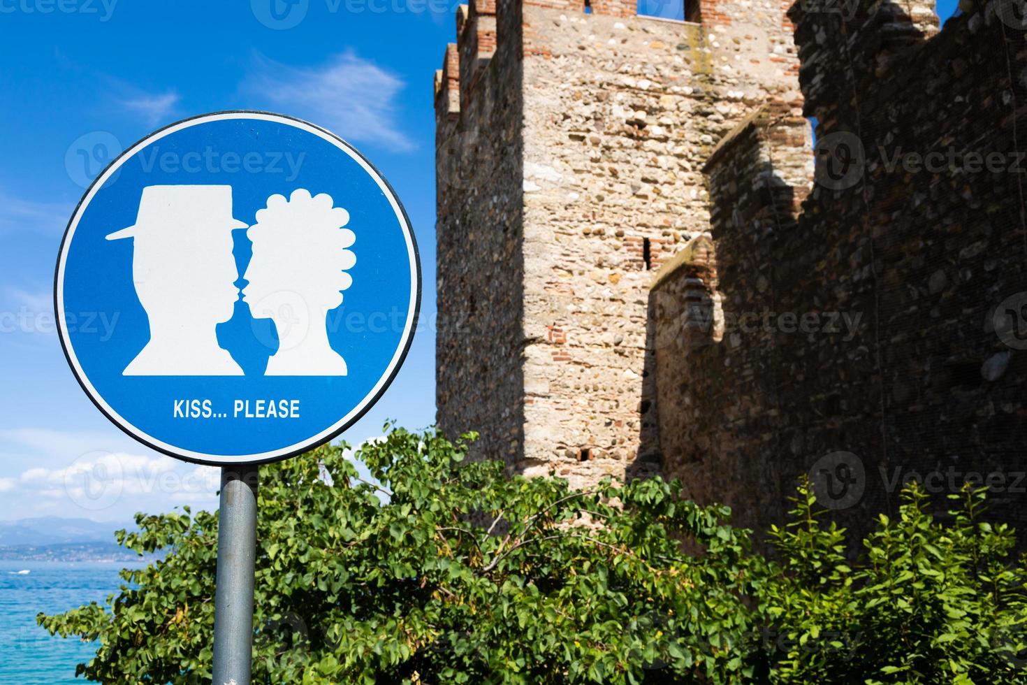 Kiss street sign located in public area in front of Sirmione castle, Italy. Concept of love, couple, romantic. photo