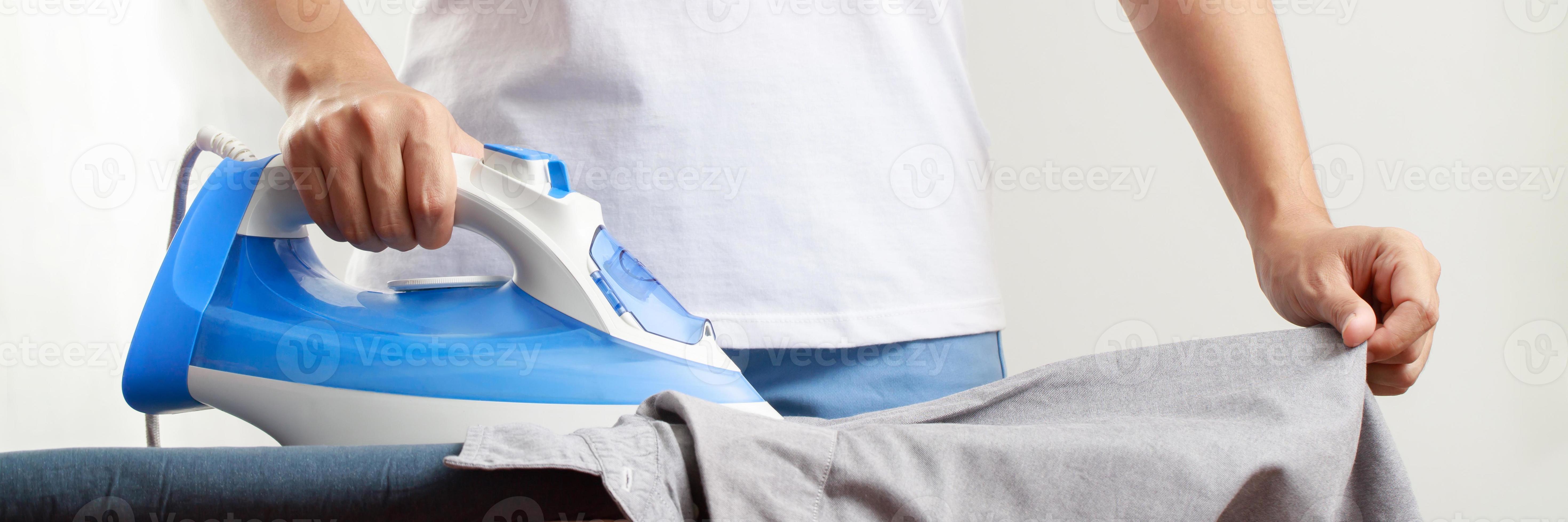 Woman at home electric ironing and pile clothes variety of colors