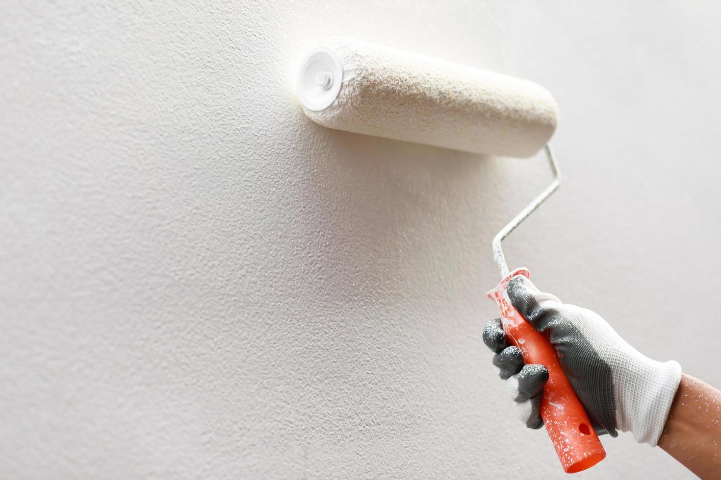 Roller Brush Painting, Worker painting on surface wall  Painting apartment, renovating with white color  paint. Leave empty copy space to write descriptive text beside. photo