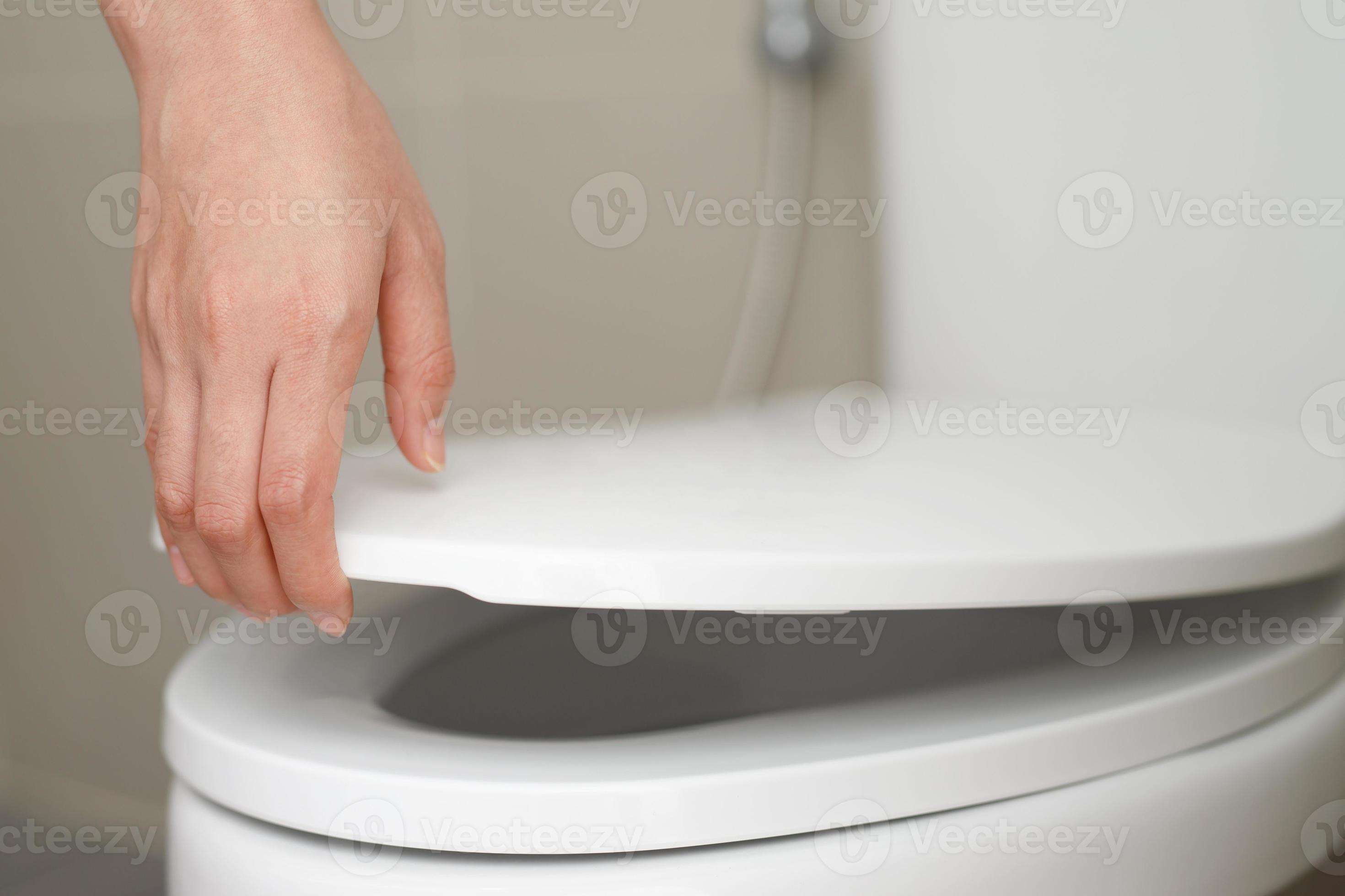 close up hand of a woman closing the lid of a toilet seat. Hygiene and