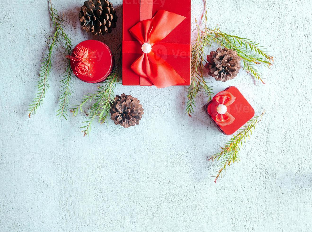Christmas decoration composition on white background with a beautiful Red gift box with red ribbon, tree branches, and pine cones photo