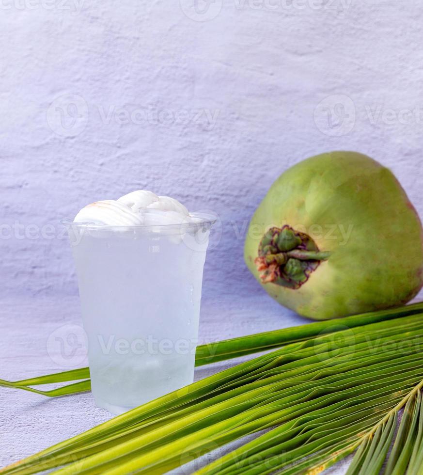 Ice coconut water drink in a plastic glass and coconut on white background photo