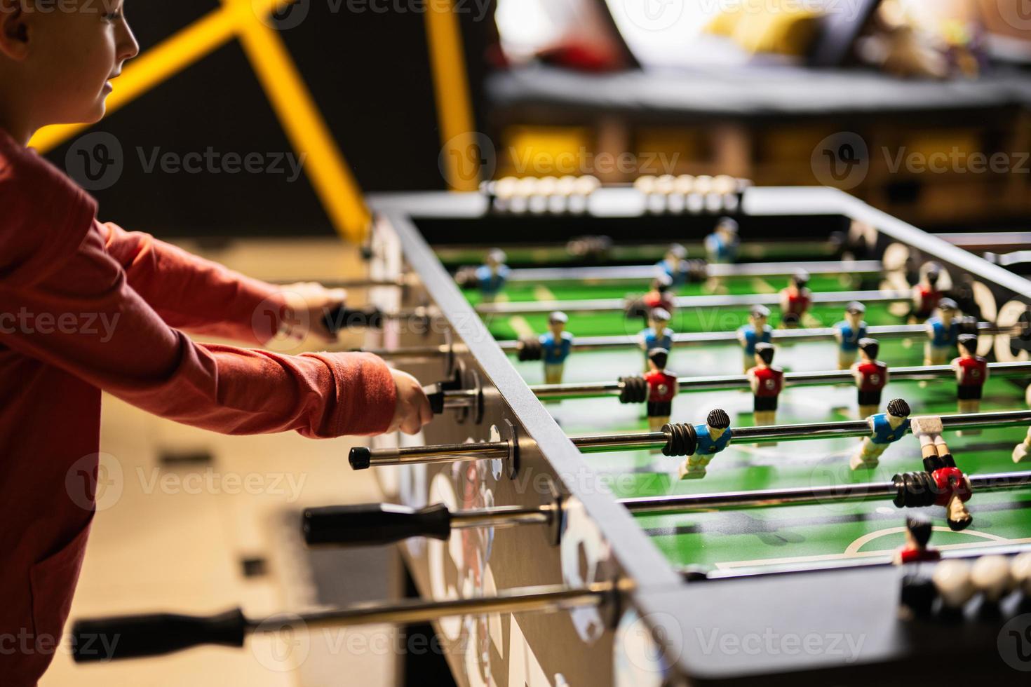 Boy playing table football in kids play center. photo