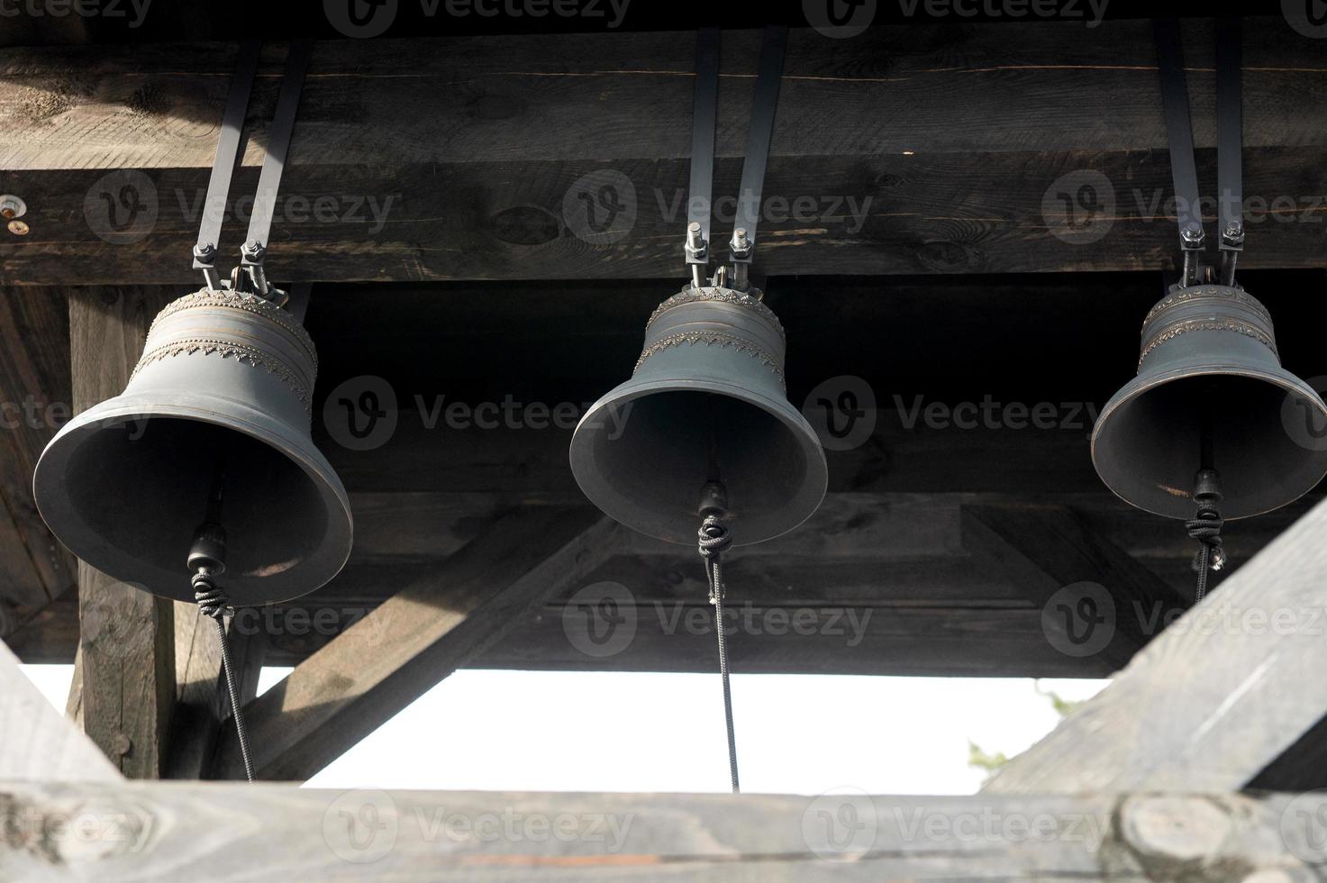 Wooden bell tower. Three black bells. Belarus, Minsk, March 2023, photo