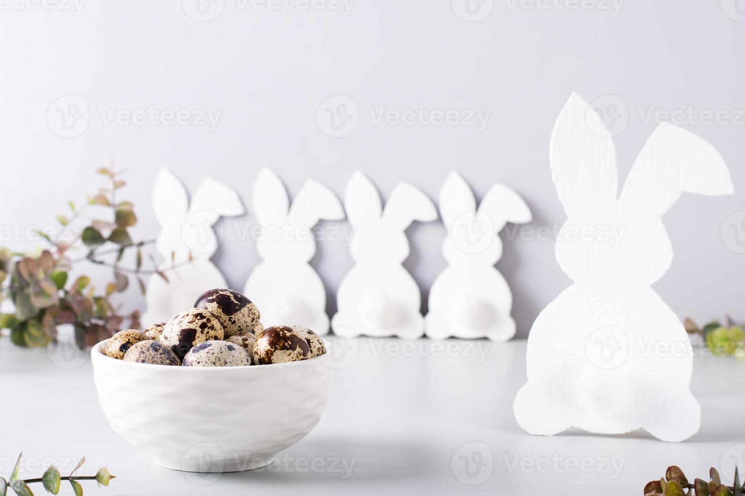 Quail eggs in a bowl and a family of white rabbits on the table for a happy easter. photo