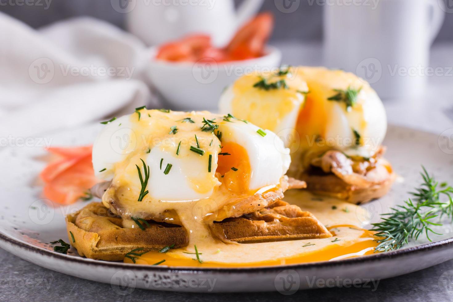 Eggs benedict and bacon on a crispy waffle on a plate for homemade breakfast photo