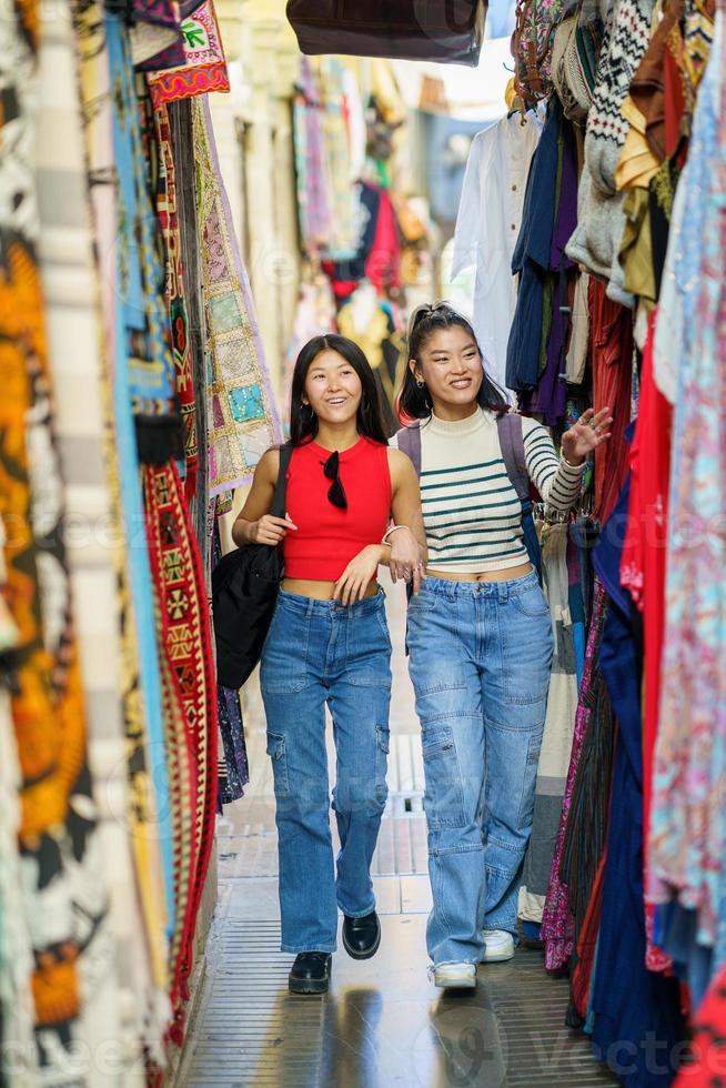 Female tourists shopping clothes in street bazaar photo