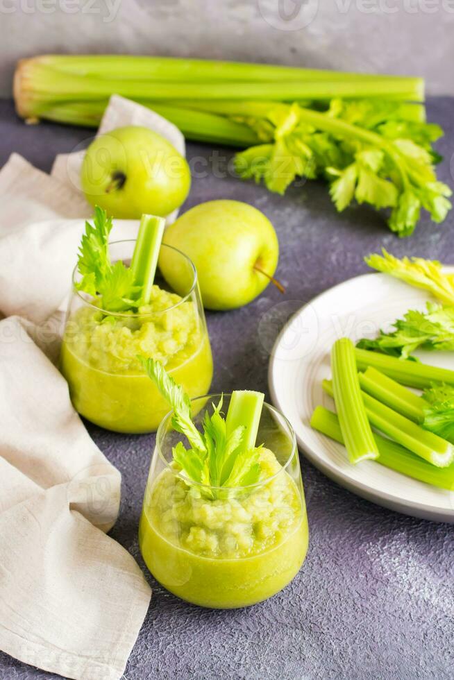 Two glasses with fresh celery and green apple smoothie and cooking