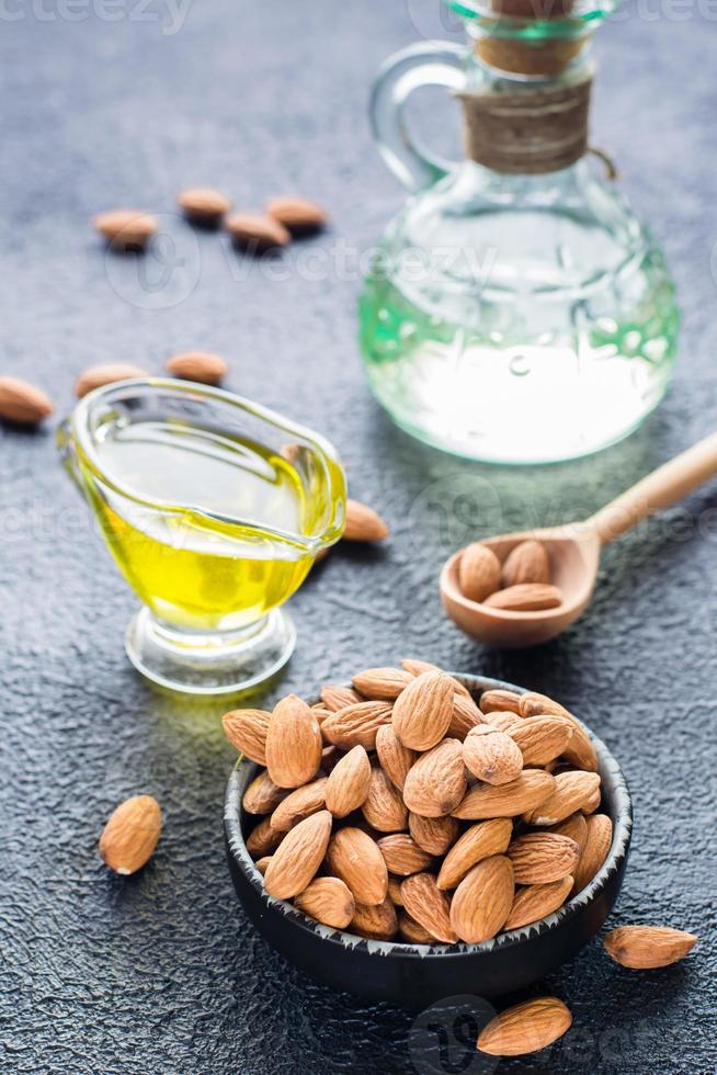 Fresh peeled almonds in a bowl and almond oil on the table. A source of vitamins and oils. Natural cosmetics. Vertical view photo