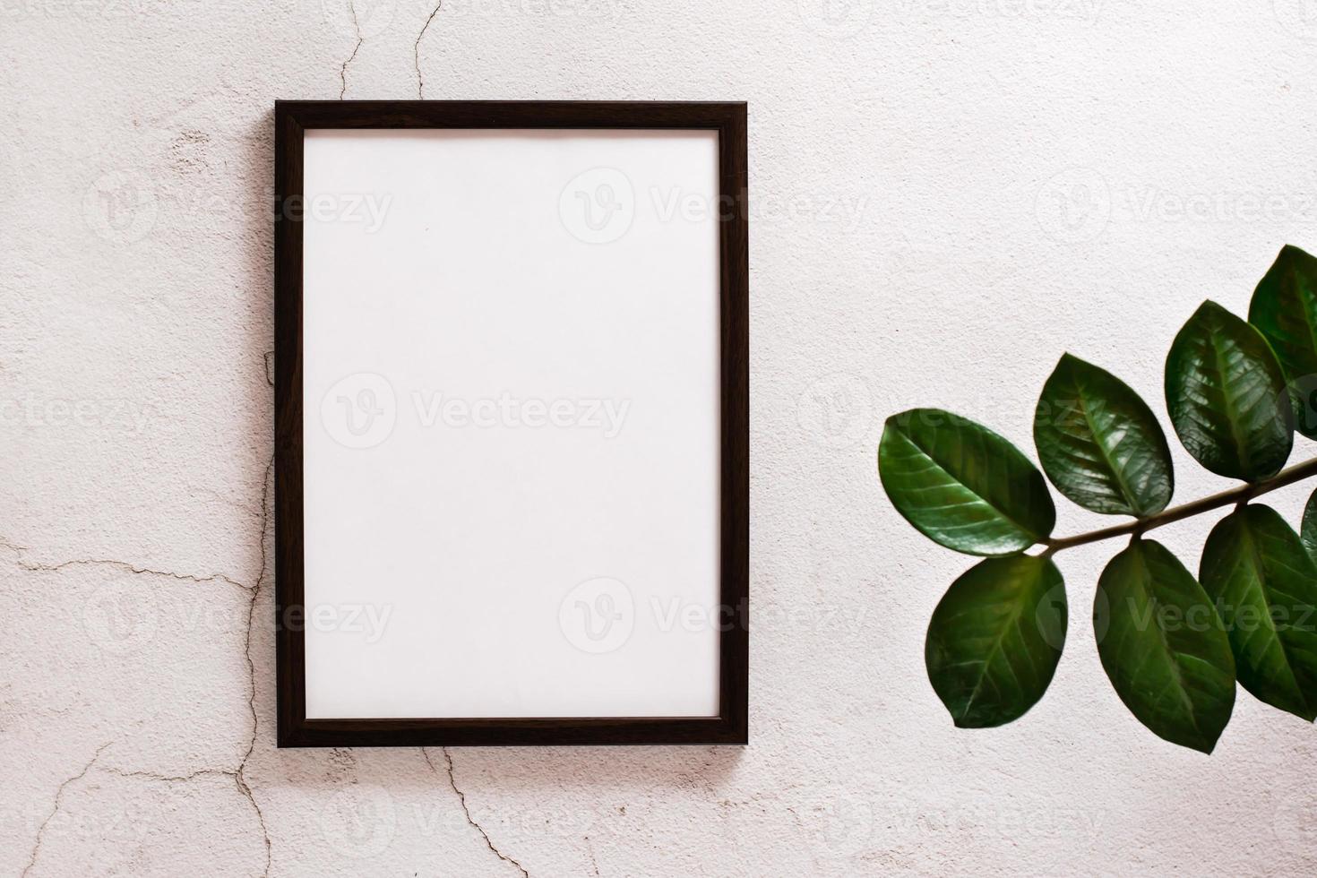 Eco mock up. Empty frame with a blank sheet on a light concrete background and leaves of home plants. Copy space. Top view. photo