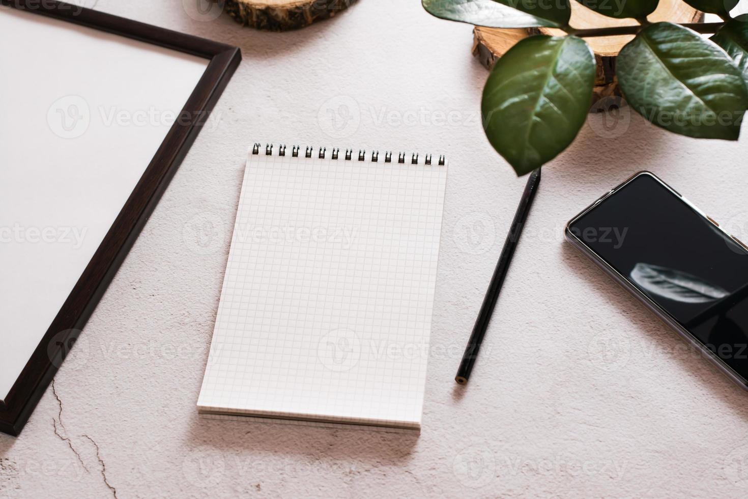 Eco desk. Open notepad, pencil and smartphone on a light concrete background. The concept of choosing means for writing. photo