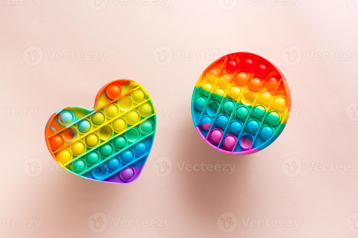 Two silicone rainbow antistress toys on a pink background. A modern way to relax photo