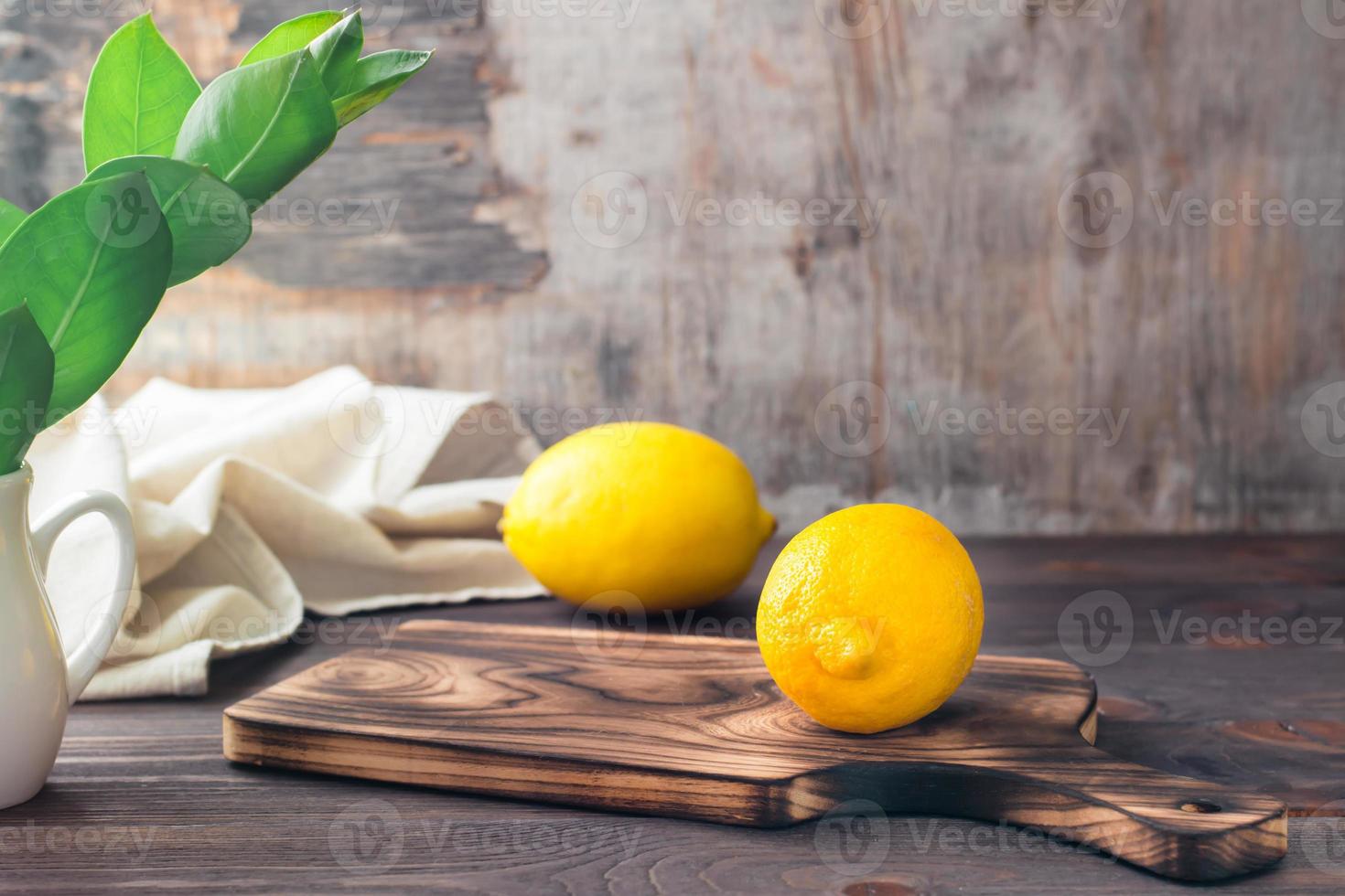 Whole ripe lemons on a wooden cutting board on the table. Organic nutrition, source of vitamins. Copy space photo